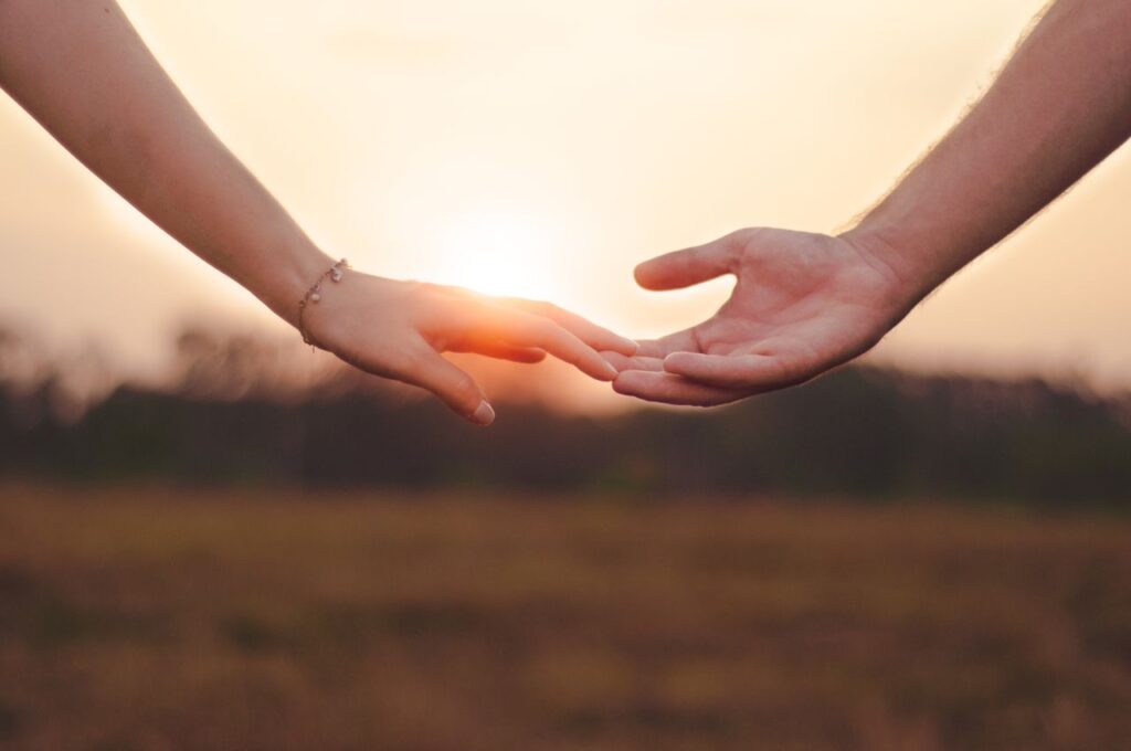 pexels photo 6343599 Crop anonymous female with bracelet touching hand of unrecognizable male in field against sundown