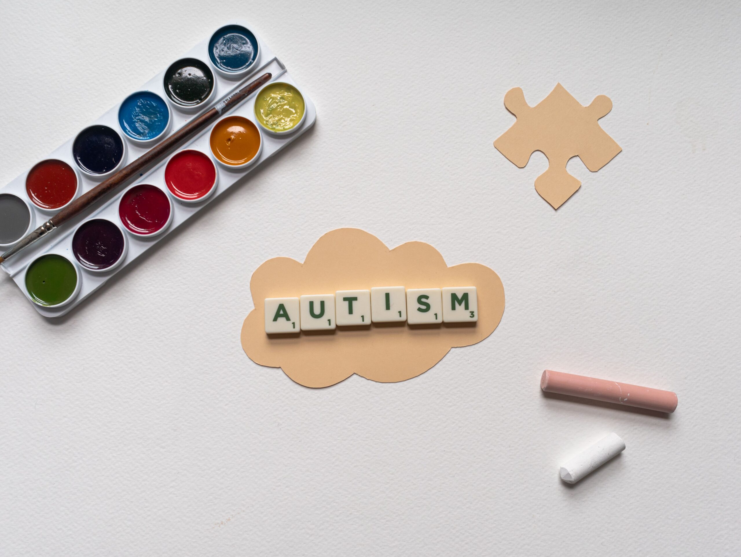 Flat lay of autism awareness concept with art materials and puzzle piece.